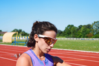 Runner on a track in white-framed sport sunglasses checking her watch