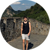 UGC photo — A man wearing a black tank top and light-colored shorts stands on a stone pathway